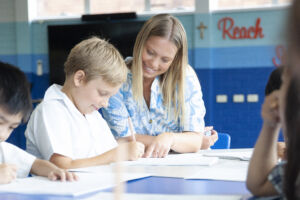 Teacher and students using workbooks for a mathematics task